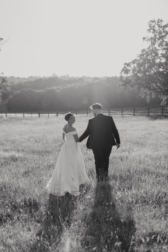 Bride and groom surrounded by long grass and golden evening light