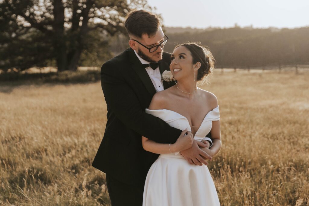Bride and groom walking through the fields during golden hour