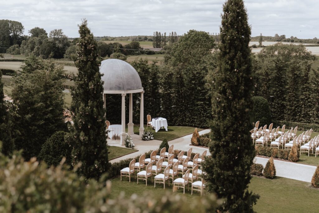 Outdoor wedding ceremony surrounded by creamy flowers and green foliage at Marquis Suffolk