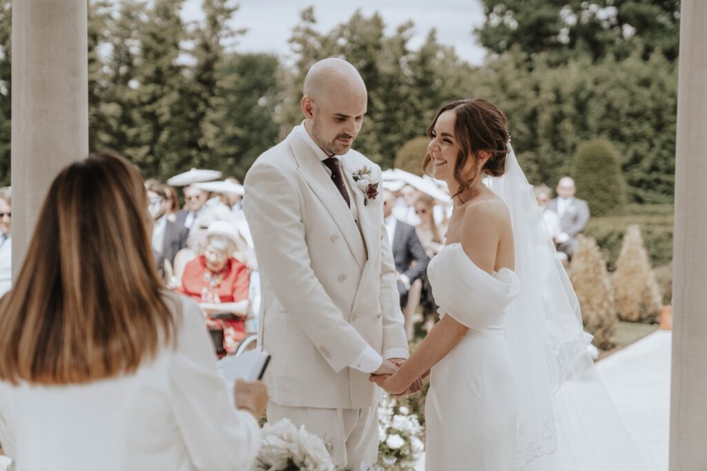 Cream wedding flowers and greenery surrounding Lauren and James' ceremony
