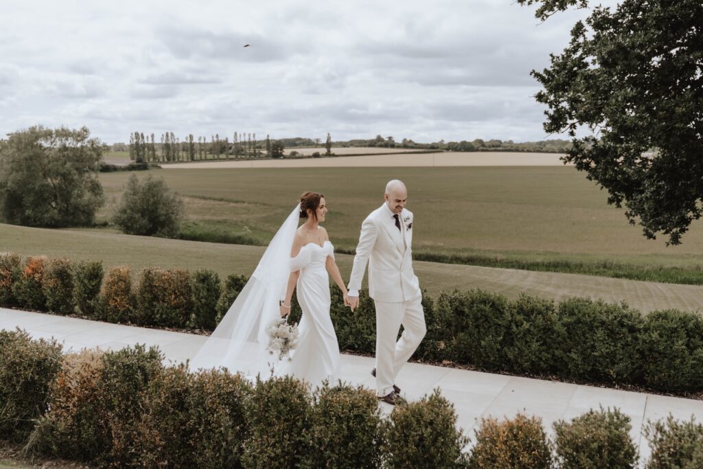 Lauren and James walking together through the gardens at Marquis Suffolk