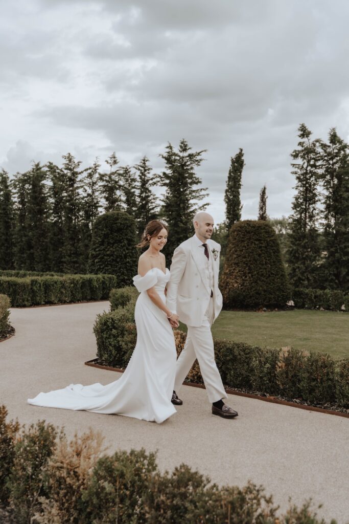 Bride and groom walking through the gardens in the soft evening light