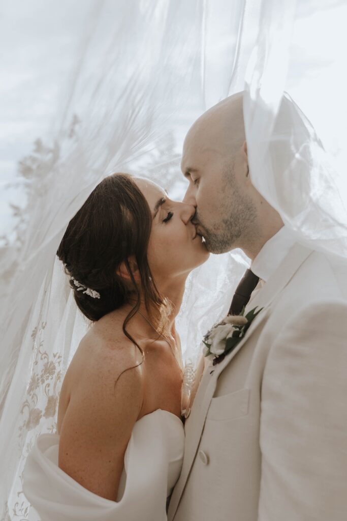 Bride and groom surrounded by greenery during evening portraits