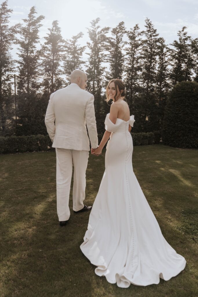 Bride and groom walking through the gardens during their Suffolk wedding