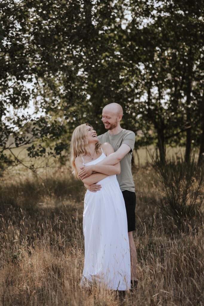 Shannon and Dom walking hand in hand through the grounds of Snape Maltings in Suffolk