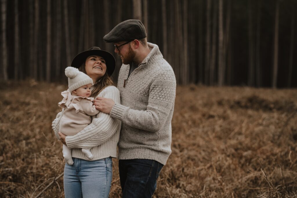 Parents cuddling their daughter during their relaxed family session in Norfolk