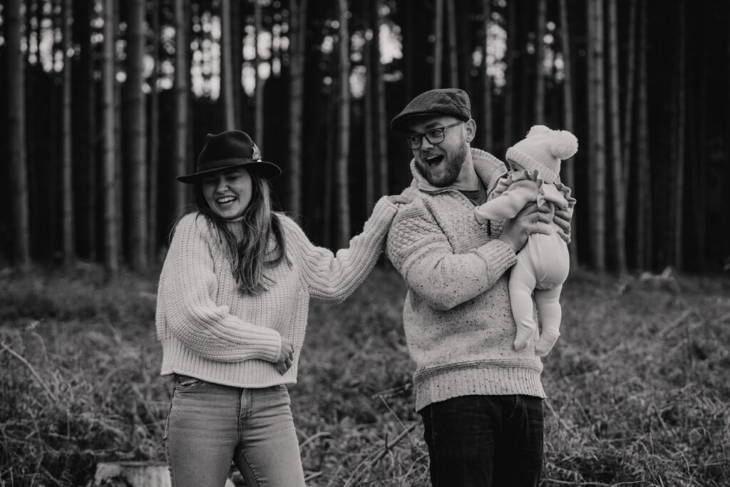 Little girl running through the woodland at Thetford Forest with her parents