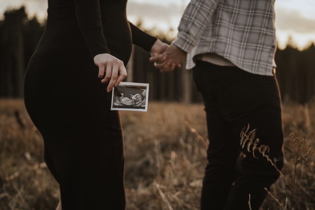 Pregnant woman standing amongst the trees at Thetford Forest during her maternity session