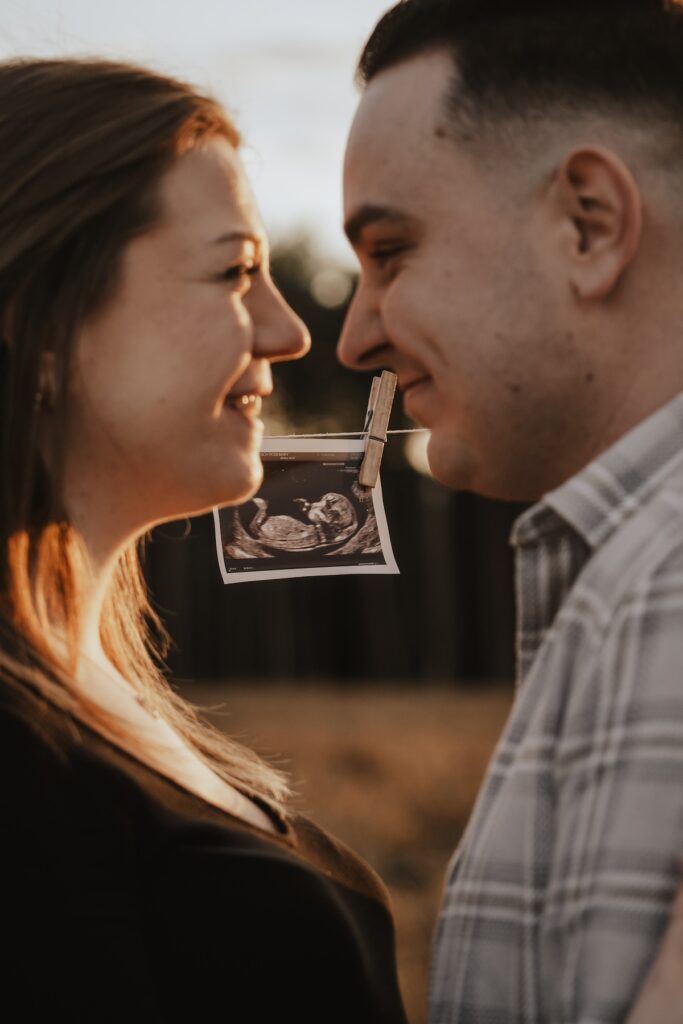 Pregnant woman and her partner cuddling together in the golden evening light