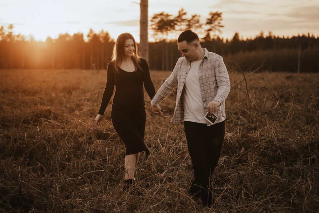 Couple walking through Thetford Forest together as they prepare to welcome their daughter