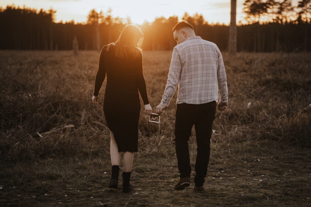 Pregnant woman looking lovingly at her partner during their golden hour maternity session